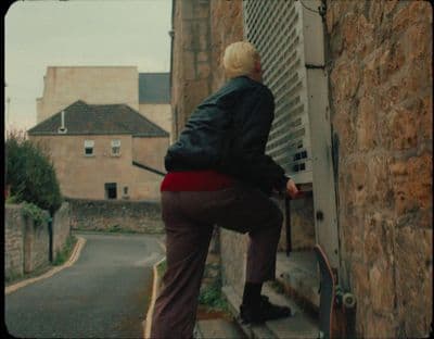a person with a skateboard leaning against a wall