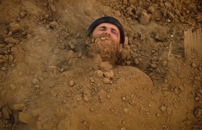 a man with a beard is buried in the dirt