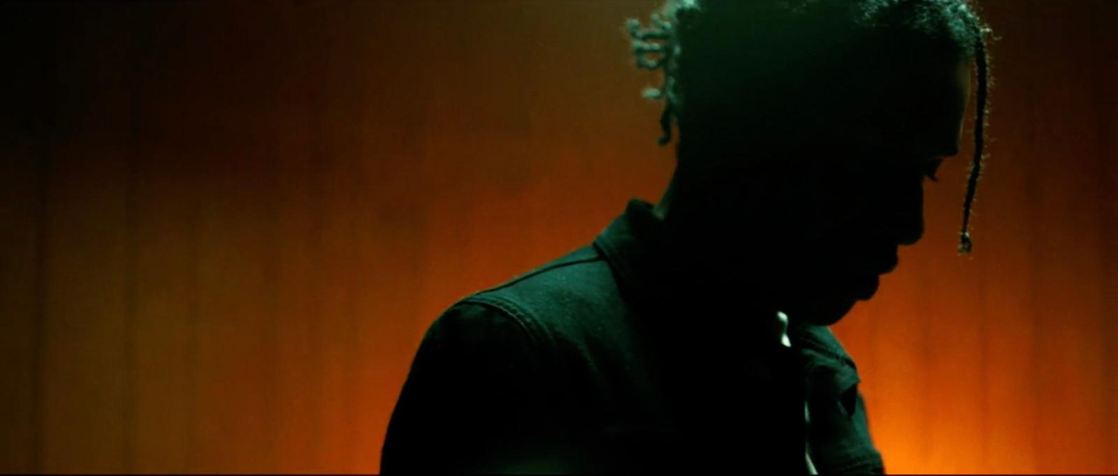 a man with dreadlocks standing in a dark room