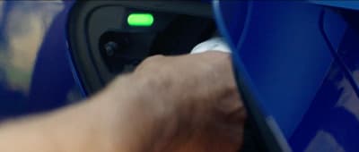 a hand is pressing a button on a blue car