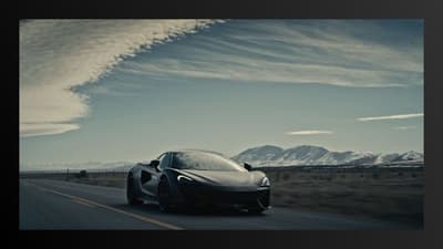 a car driving down a road next to snow covered mountains