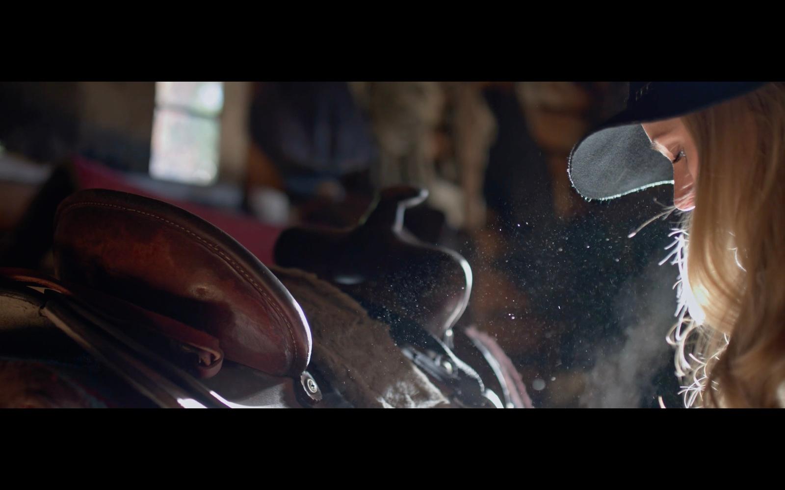 a woman looking at a horse's saddle through a window