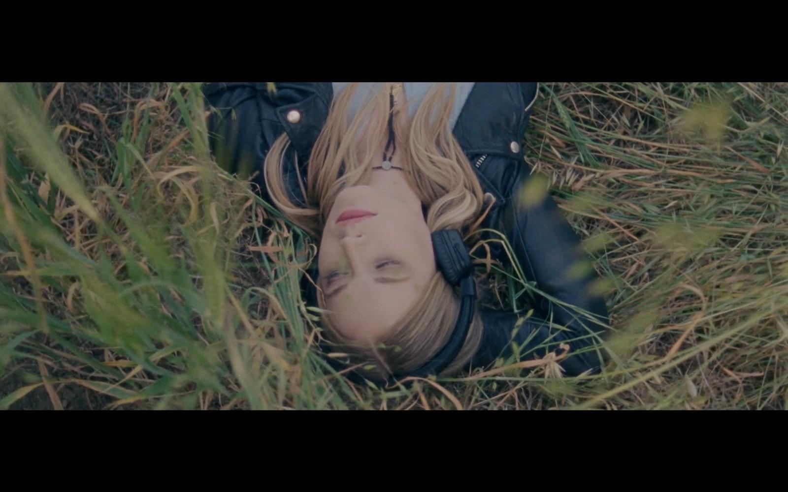 a woman laying in the grass with her eyes closed