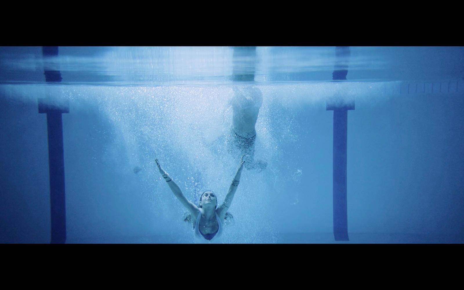 a man swimming in a pool with his hands in the air