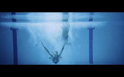 a man swimming in a pool with his hands in the air