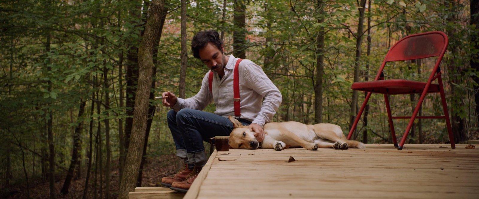 a man sitting on a deck with two dogs