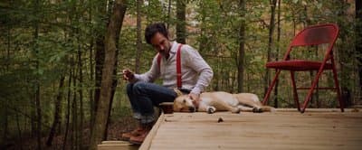 a man sitting on a deck with two dogs