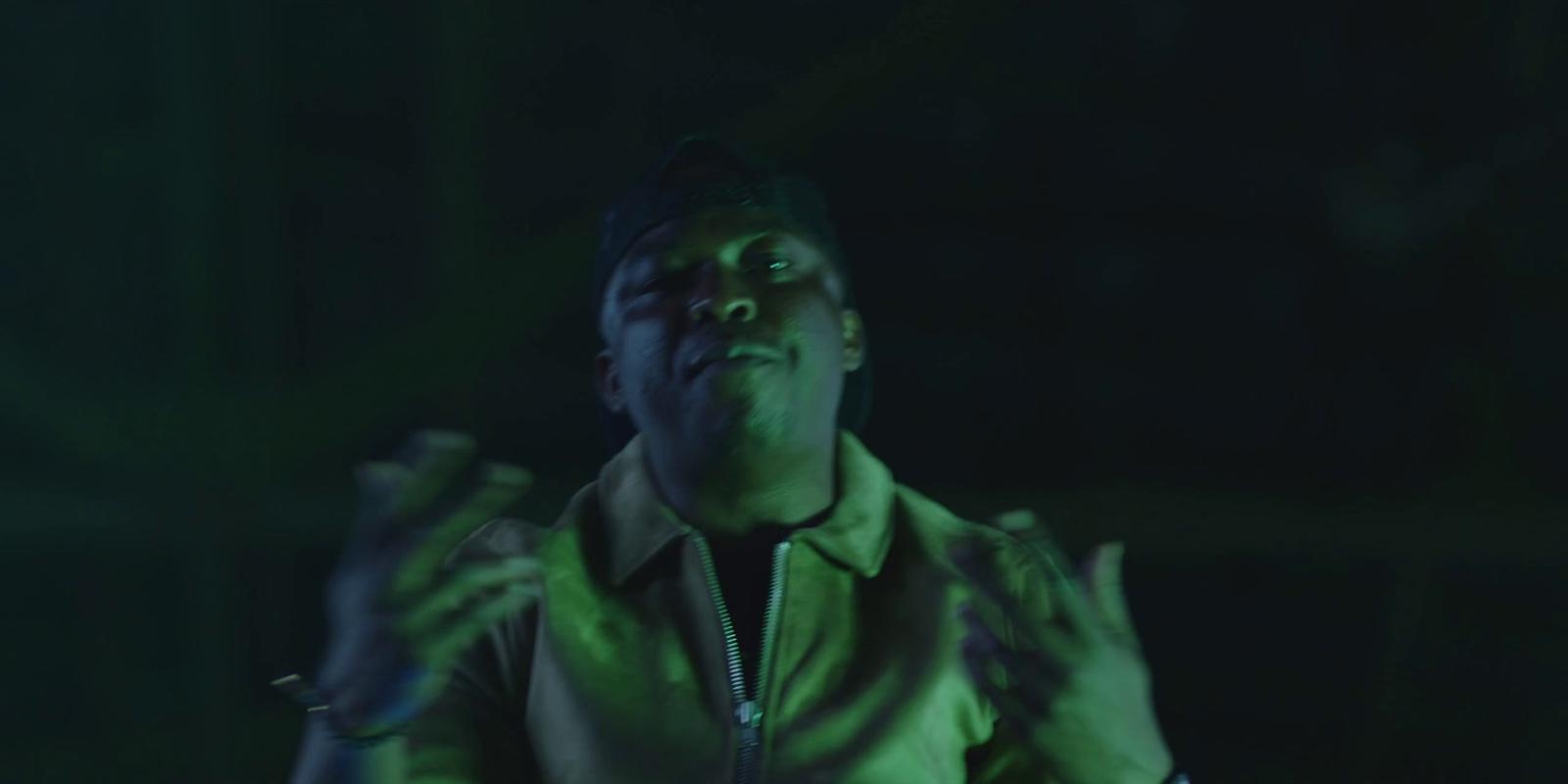 a man in a green jacket with his hands up in the air