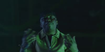 a man in a green jacket with his hands up in the air