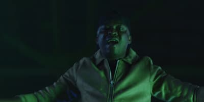 a man in a green jacket with his arms outstretched