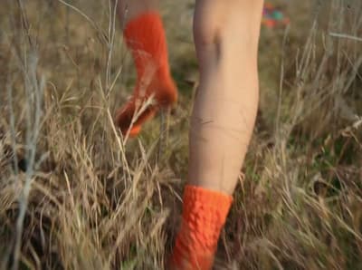 a person with orange socks walking through a field