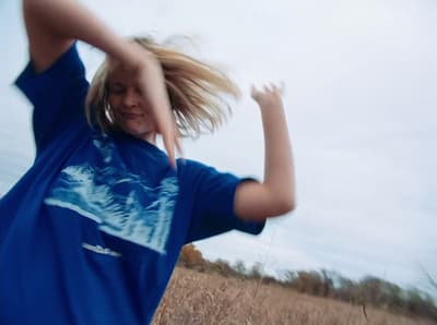 a girl in a blue shirt throwing a frisbee