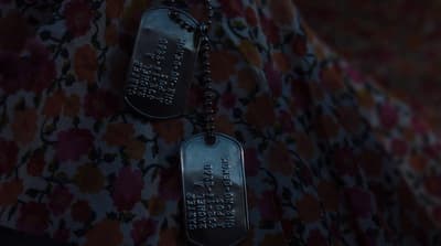 two dog tags hanging from a chain on a wall