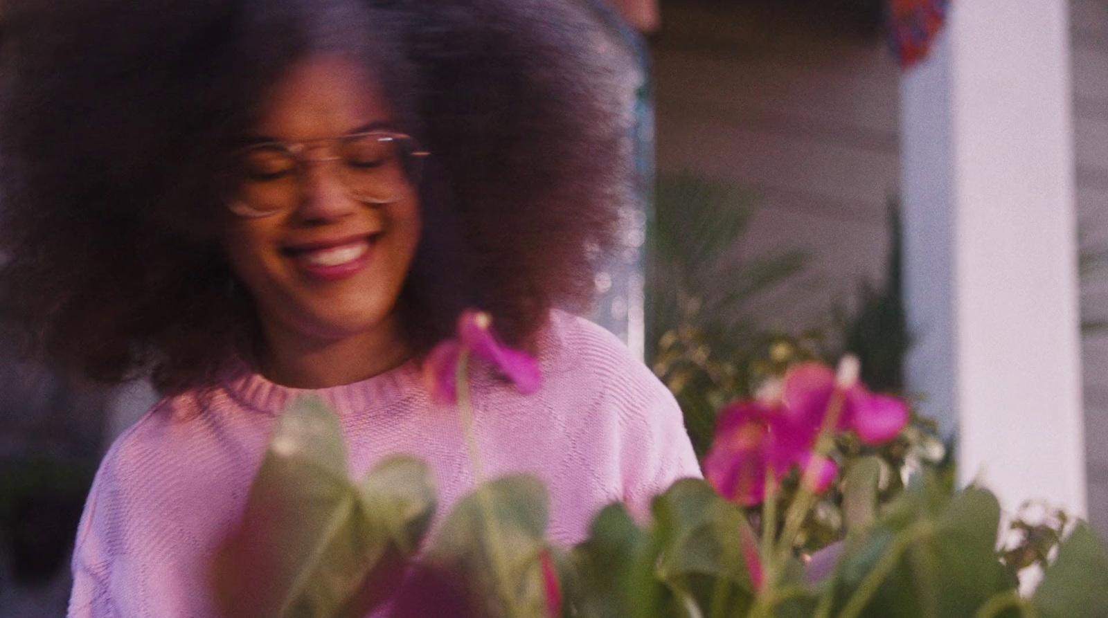 a woman with glasses standing next to a potted plant