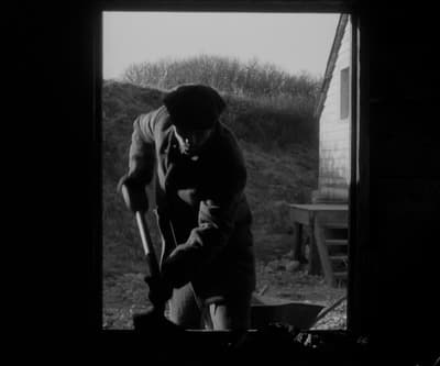 a black and white photo of a man holding a shovel