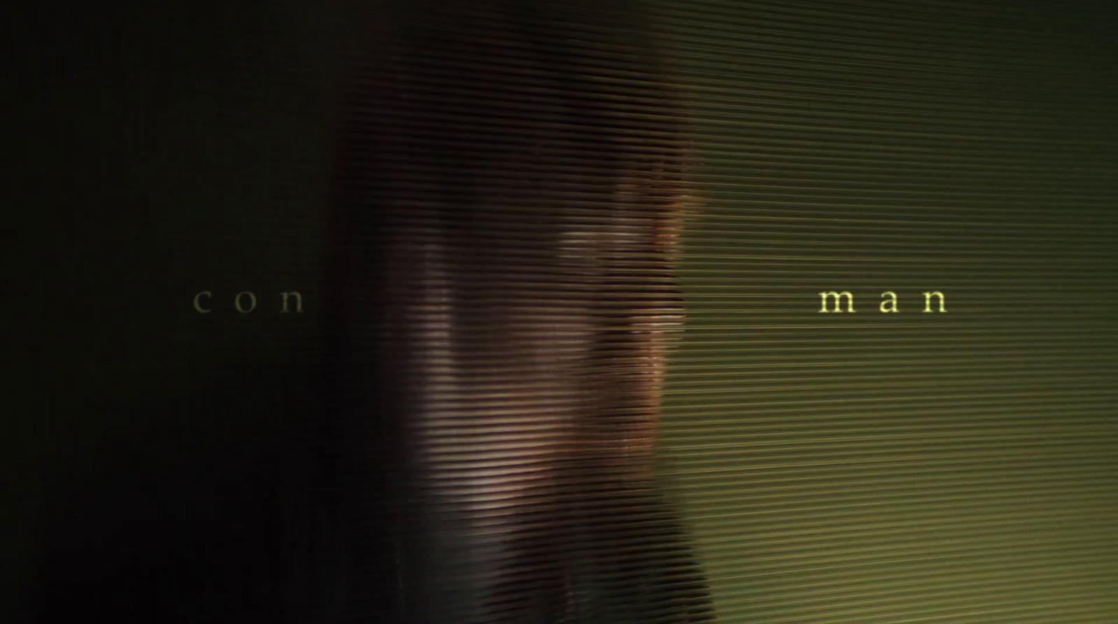 a blurry image of a woman's face with the words con man in