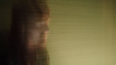 a blurry photo of a woman's face behind blinds