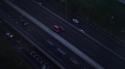 a red car driving down a highway next to tall buildings