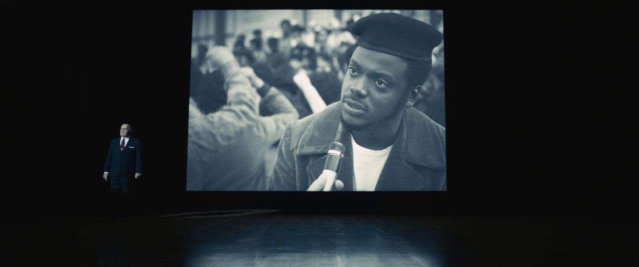 a man standing in front of a large screen
