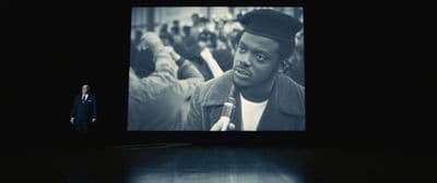 a man standing in front of a large screen