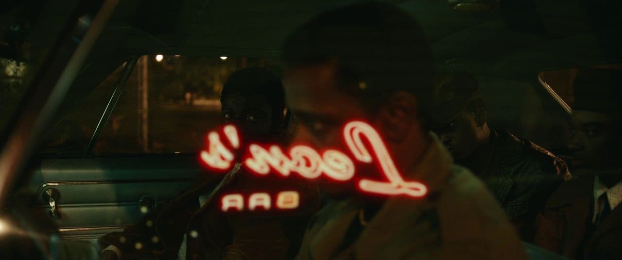 a man sitting in a car holding a neon sign