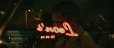 a man sitting in a car holding a neon sign