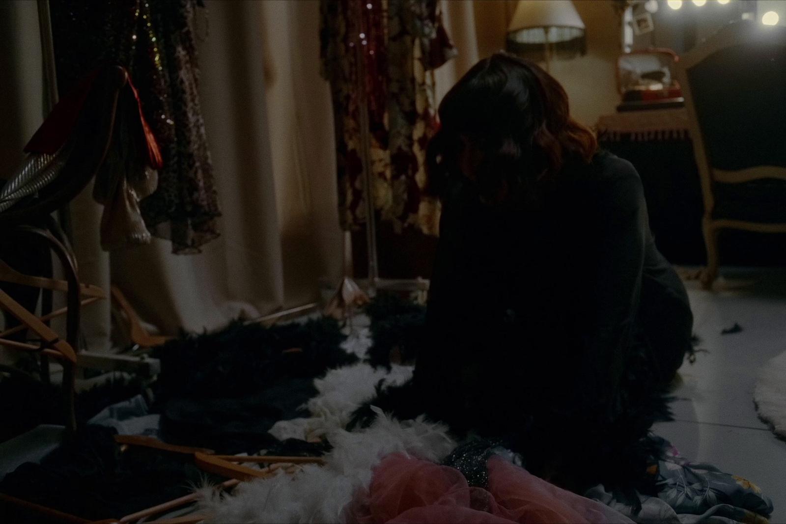 a woman sitting on the floor next to a pile of clothes