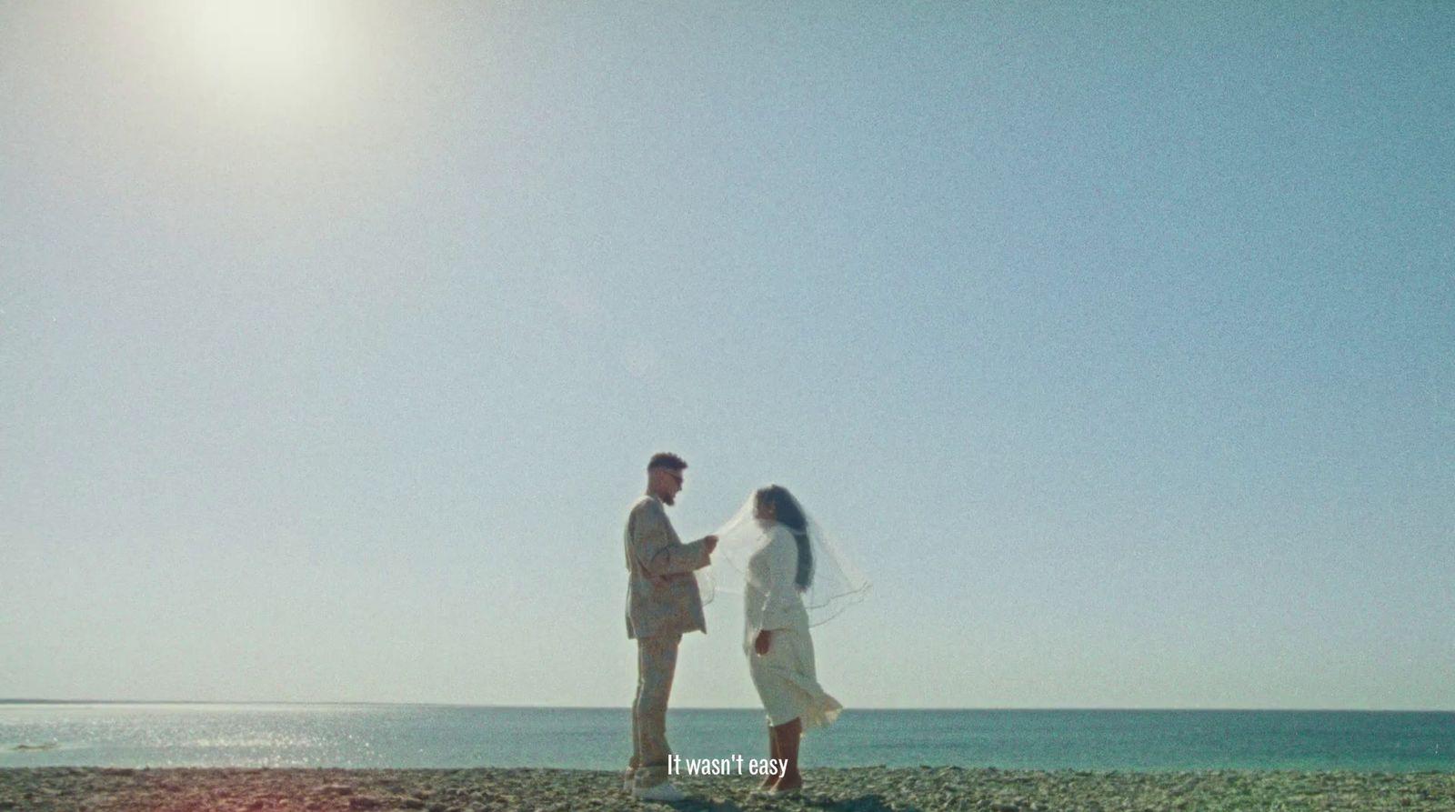 a man and woman standing on a beach next to the ocean