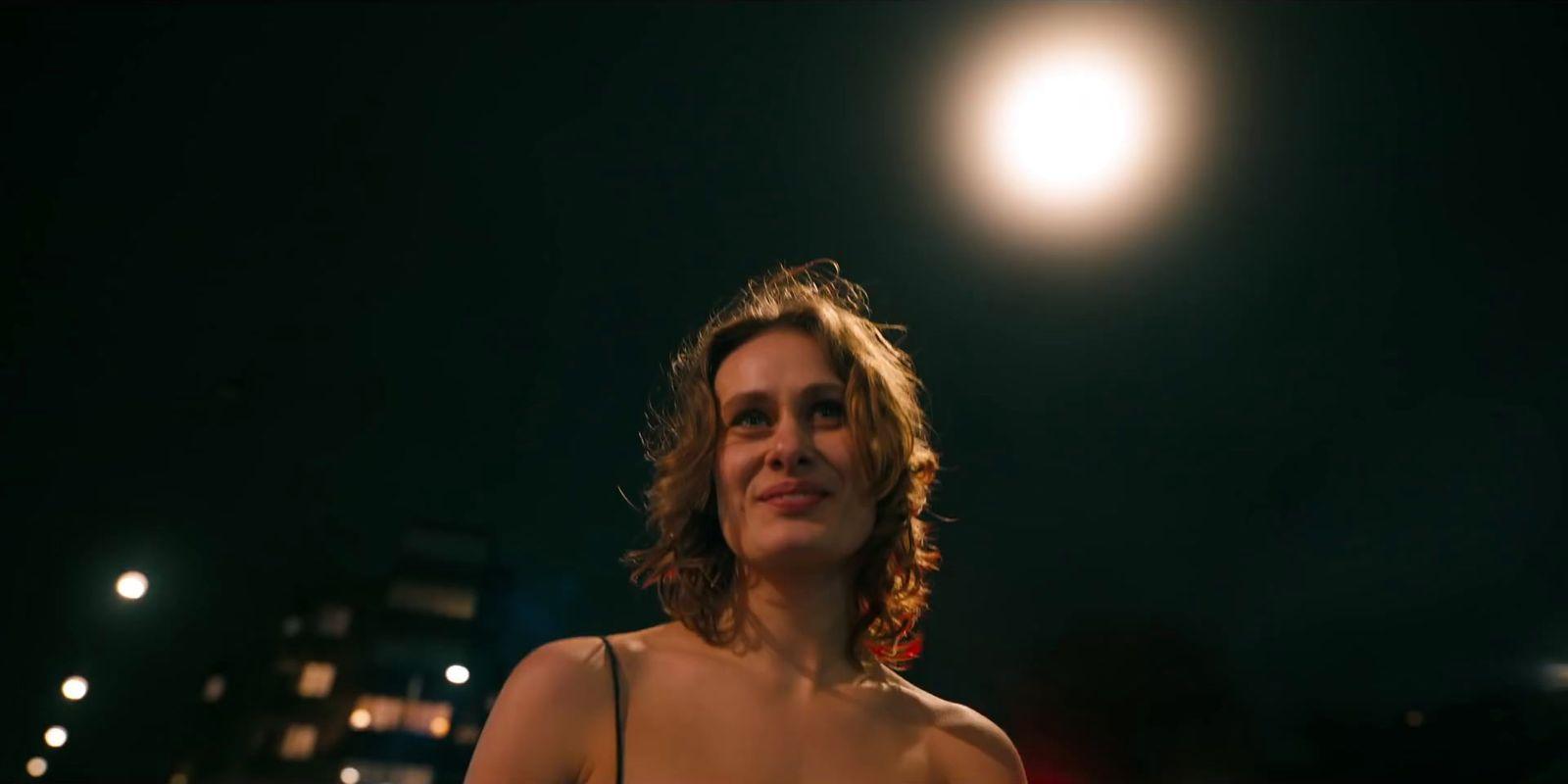 a woman standing in front of a street light at night
