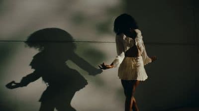 a shadow of a woman standing next to a wall