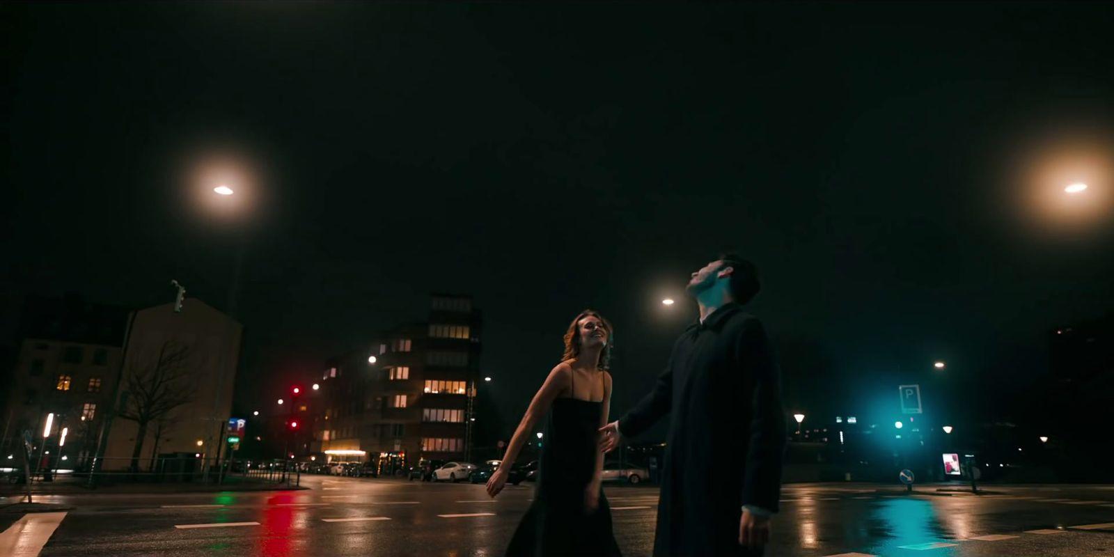 a man and a woman walking across a street at night