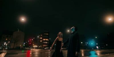 a man and a woman walking across a street at night