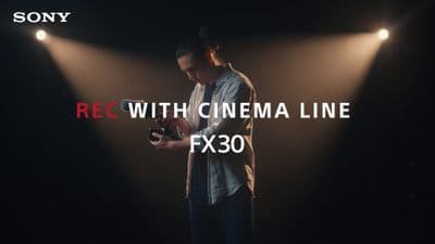 a man holding a camera in front of a dark background