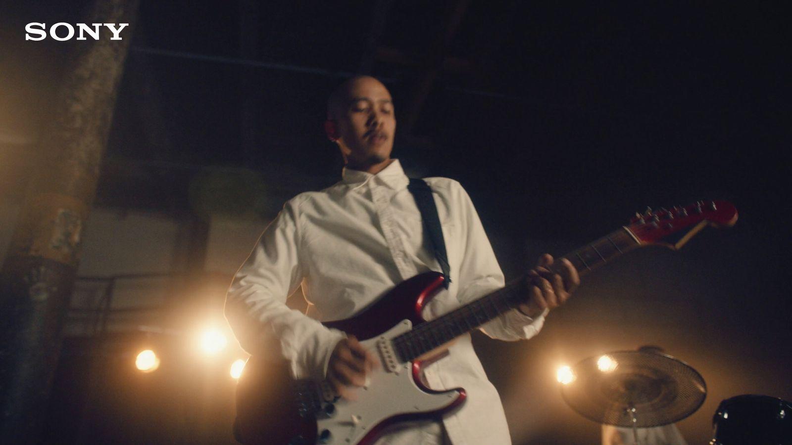 a man in a white shirt and tie playing a guitar