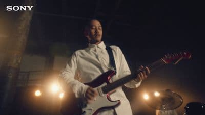 a man in a white shirt and tie playing a guitar