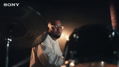 a man with glasses playing drums in a dark room