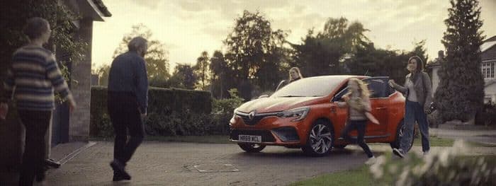 a group of people standing around a red car