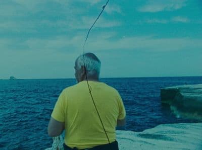 a man standing on top of a cliff next to the ocean