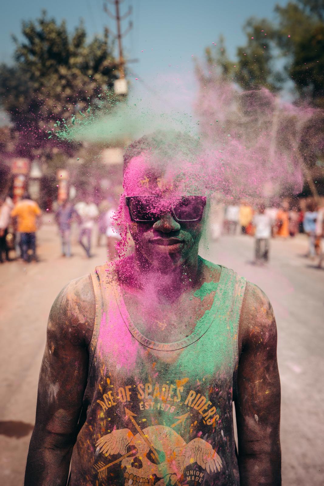 a man covered in colored powder on a street