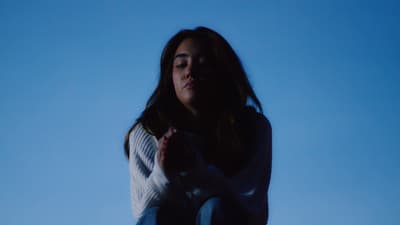 a woman sitting on the ground with her hands together