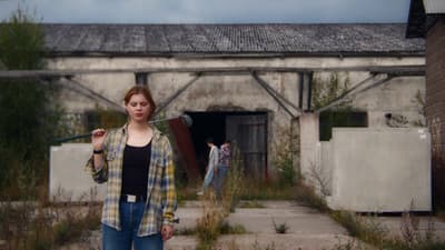 a woman standing in front of a building holding a microphone