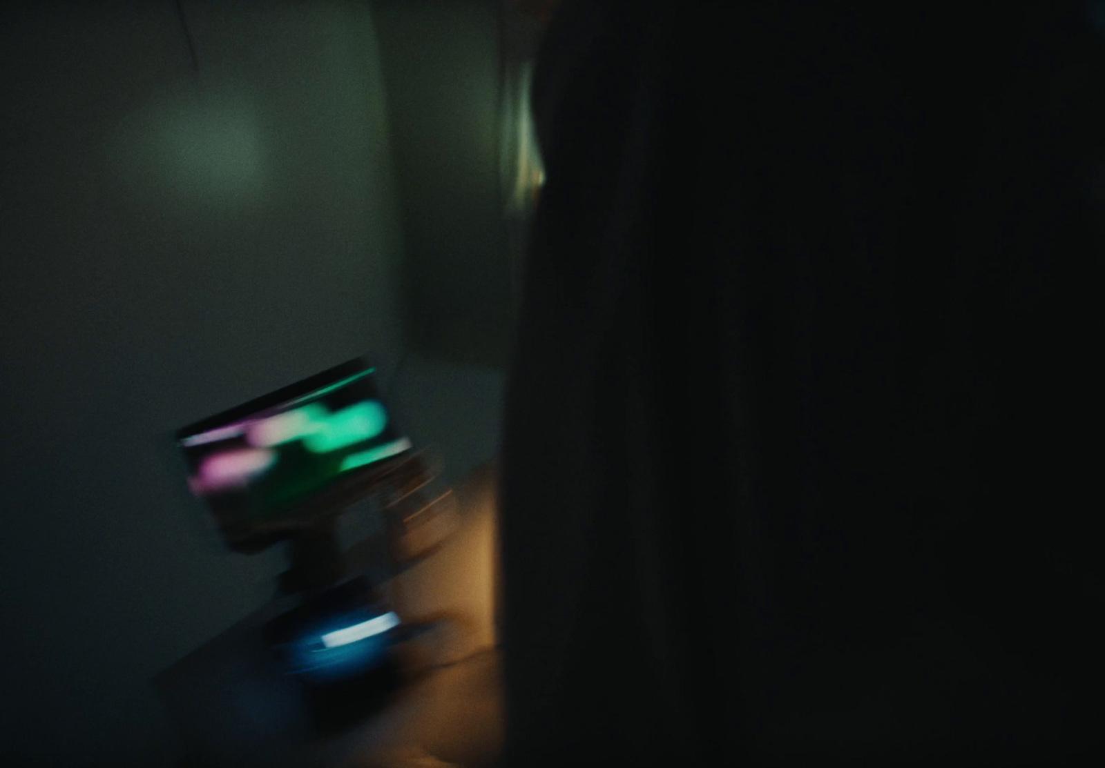 a person standing in a dark room looking at a television
