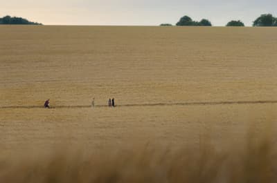 a group of people walking across a dry grass field