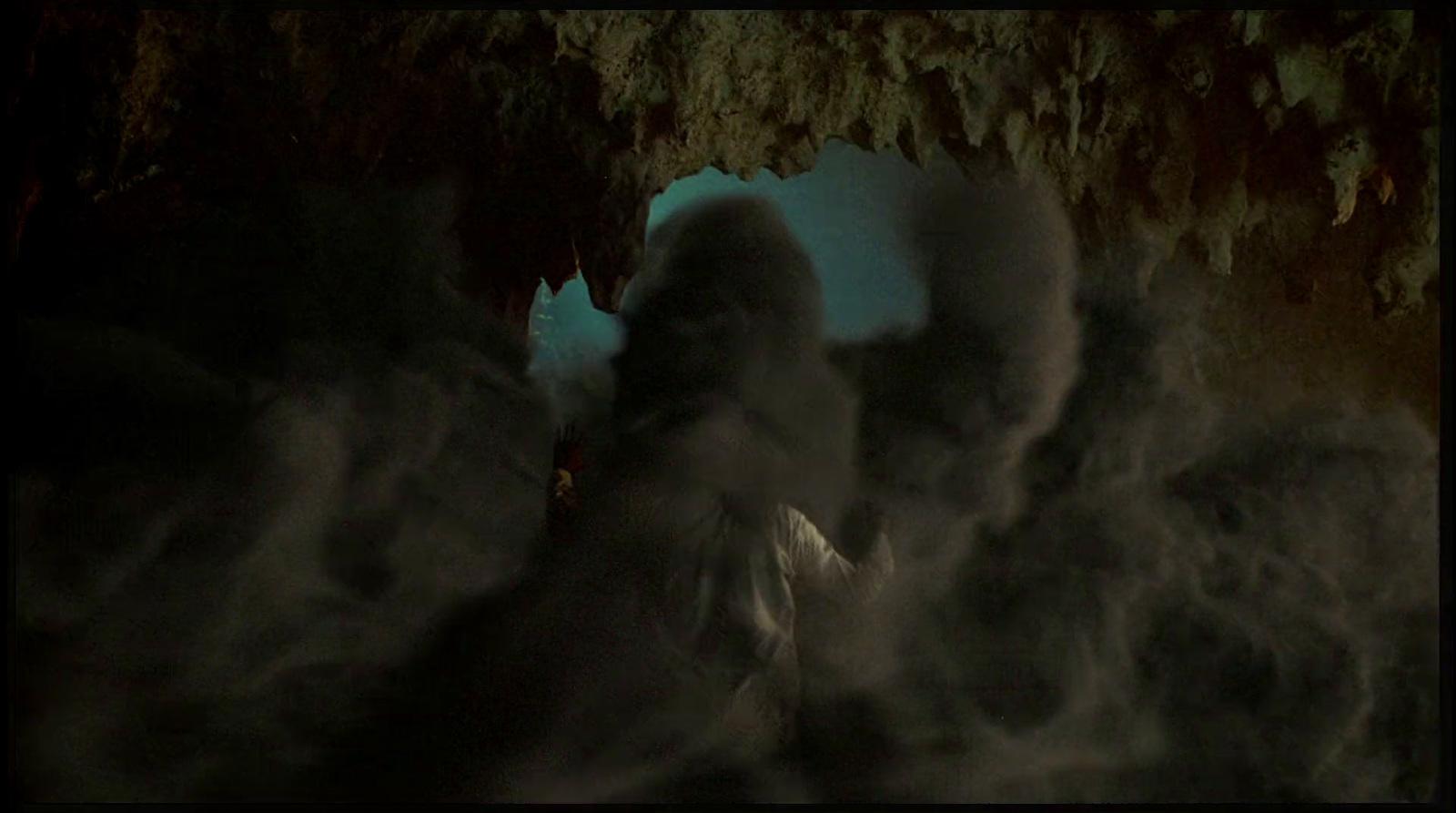 a man standing in a cave with smoke coming out of it