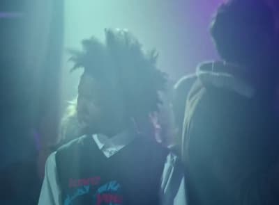 a man with dreadlocks standing in front of a crowd