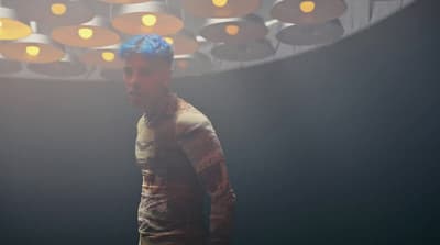 a man with blue hair standing in a room