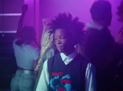 a young man with dreadlocks standing in front of a group of people