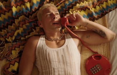 a man laying on a bed talking on a phone