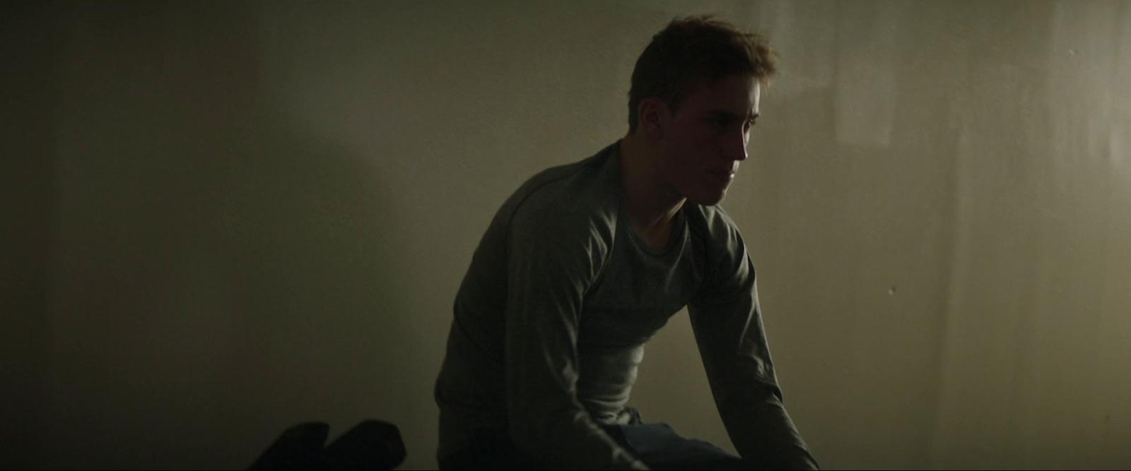 a man sitting on a bed in a dark room