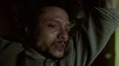 a man in a sweater is holding his hands up to his head